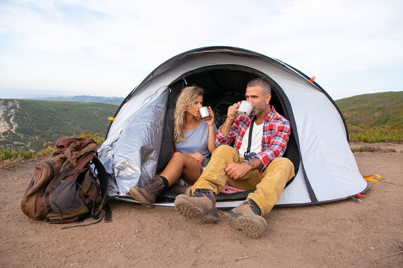 services-03 A couple enjoys coffee while sitting outside their tent with a scenic view, embodying a sense of adventure and relaxation.